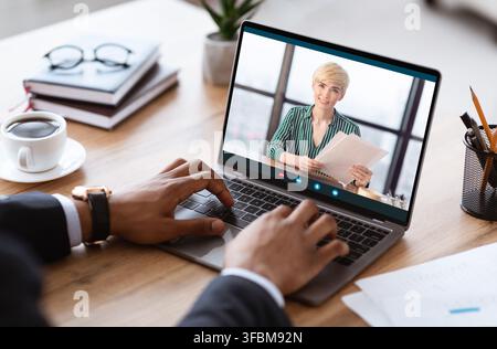 Homme d'affaires noir méconnaissable ayant un jeu vidéo avec un partenaire d'affaires, utilisant un ordinateur portable Banque D'Images