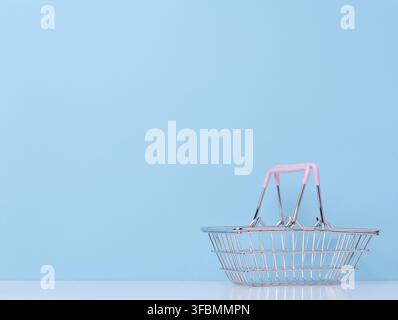Vide miniature chariot de métal pour supermarché sur fond bleu. Copier l'espace Banque D'Images