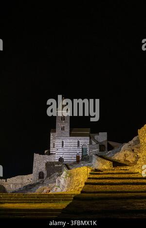 Vue de l'église historique de Saint-Pierre à Portovenere avec sa façade en pierre rayée noir et blanc distinctive illuminée la nuit, featuring stone Banque D'Images