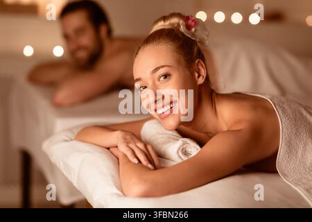 Femme au massage en couple souriant couché sur le lit au spa Banque D'Images