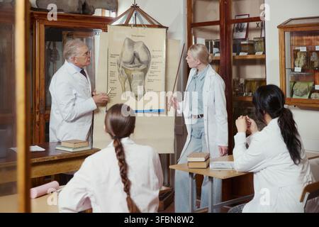 Professeur caucasien senior et jeune assistante caucasienne enseignant l'anatomie à des étudiants divers dans une salle de classe universitaire, idéal pour le marketing de l'éducation médicale Banque D'Images