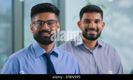 Portrait de deux collègues arabes, hommes d'affaires, collègues musulmans souriants, hommes d'affaires hindous, partenaires masculins, managers, hommes d'affaires ensemble en train de regarder Banque D'Images