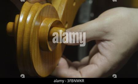 Luthier examinant soigneusement et ajustant une cheville d'accord en bois finement conçue, assurant un ajustement précis et un fonctionnement fluide pour un mécanisme d'accord de violoncelle Banque D'Images