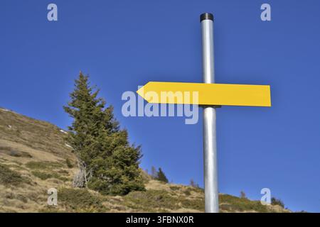 Panneau indicateur jaune vierge sur un poteau métallique montrant la direction contre un ciel bleu clair Banque D'Images