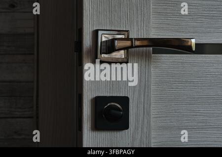 Ensemble complet de serrure de porte moderne avec poignée métallique sombre et mécanisme de verrou rotatif carré en gros plan Banque D'Images