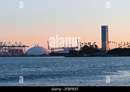 Des grues portuaires, des navires et une tour d'île du port se dressent au-dessus d'une eau bleue. Banque D'Images