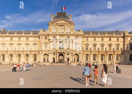 PARIS, FRANCE - 20 JUIN 2026 : Les touristes traversent la Cour Napoléon en direction du Pavillon Sully du musée du Louvre. Banque D'Images