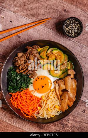 Bibimbap avec des légumes colorés, du bœuf et de l'œuf dans un bol Banque D'Images