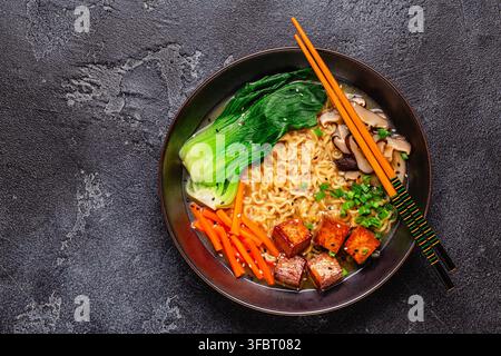 Soupe miso ramen aux nouilles servie avec du tofu, du bok choy, des carottes et des champignons dans un bol. Banque D'Images