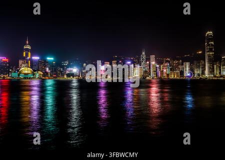 Un plan large et horizontal montre la skyline illuminée de Hong Kong la nuit, avec le célèbre International Finance Centre et la Bank of China Tower visibles Banque D'Images