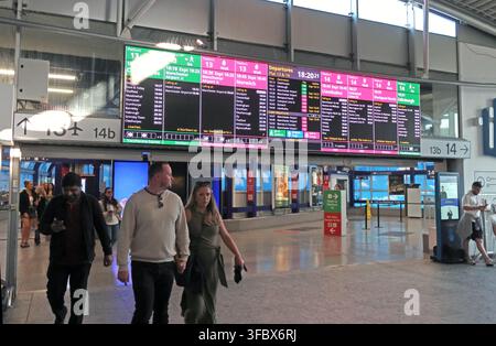 Passagers sous les panneaux d'information électroniques des départs en direct dans la gare de Manchester Piccadilly, plateformes d'étranglement 13 & 14, Angleterre, Royaume-Uni. Banque D'Images
