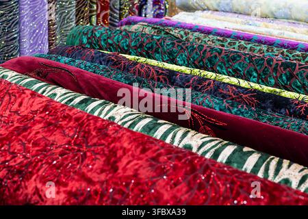 Rouleaux de velours colorés et de tissus brodés empilés sur un bazar oriental à Boukhara, Ouzbékistan. Textures riches et motifs vibrants idéaux pour le textile Banque D'Images