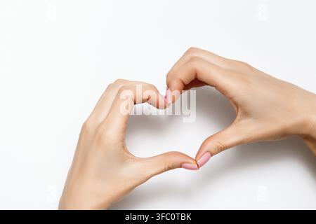 Jeune femme avec les mains montrant un signe de cœur sur un fond gris. Concept pour la Saint-Valentin, l'amour, la romance. Espace de copie vu du dessus Banque D'Images