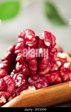 gros plan de noix de walnut rouges empilées dans un bol en bois avec un arrière-plan flou. Banque D'Images