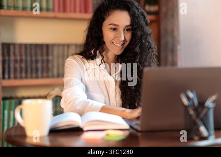 Woman sitting at desk and using laptop Banque D'Images