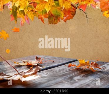 Feuilles d'érable d'automne suspendues au-dessus d'une table en bois rustique avec espace libre Banque D'Images