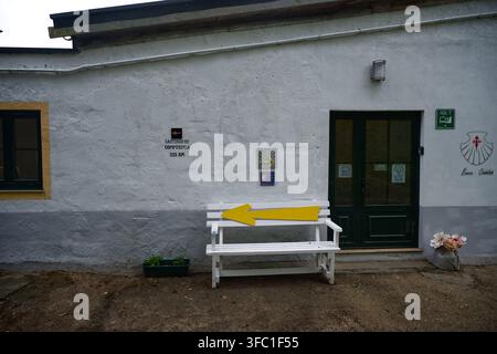 Les panneaux du Camino de Santiago et une grande flèche jaune marquent le chemin de pèlerinage à l'extérieur d'une auberge à Rellón. Banque D'Images