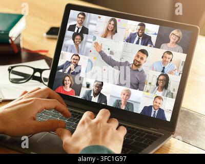 Homme d'affaires appels vidéo vers divers collègues via un ordinateur portable dans un bureau moderne Banque D'Images