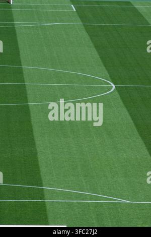 Vue verticale en portrait de l'arc du cercle central et de la ligne droite du terrain sur une pelouse de football rayée de vert. Banque D'Images