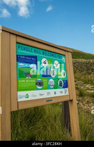 Un panneau d'information "Pendle Hill vous souhaite la bienvenue" se trouve au début d'un sentier pavé de pierres menant aux pentes herbeuses de Pendle Hill dans le Lancashire Banque D'Images