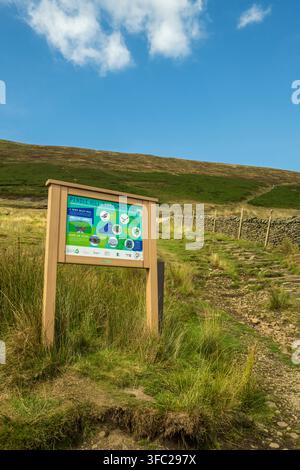 Un panneau d'information "Pendle Hill vous souhaite la bienvenue" se trouve au début d'un sentier pavé de pierres menant aux pentes herbeuses de Pendle Hill dans le Lancashire Banque D'Images