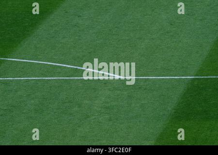 Ligne de but blanche courbée et mi-temps traversant une pelouse rayée verte avec une ombre de stade sur le terrain. Banque D'Images