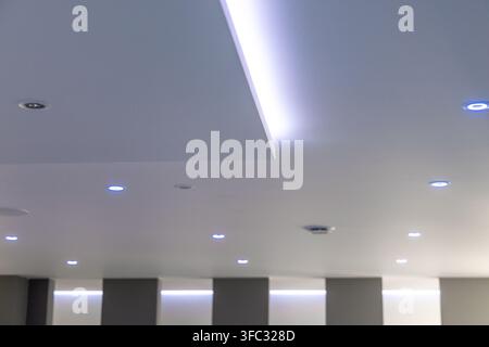 Un design de plafond d'intérieur contemporain mettant en vedette plusieurs spots encastrés et un éclairage LED à bande intégré pour une ambiance sophistiquée Banque D'Images