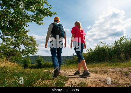 Deux adultes, une femme et un homme, randonnant sur un sentier ensoleillé à la campagne. Prise de vue en contre-plongée avec le ciel bleu. Banque D'Images