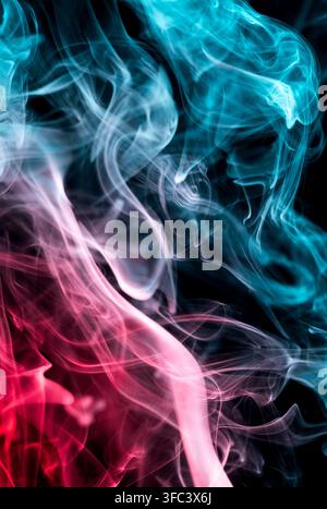 Des tourbillons de fumée cyan et rose abstraits se mêlant sur un fond noir. Banque D'Images