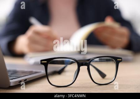 Mots-clés. Verres sur la table et femme écrivant dans un carnet, mise au point sélective Banque D'Images