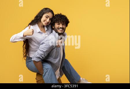 Jeune femme sud-asiatique souriante donnant un pouce levé sur le dos d'un jeune homme, émotion heureuse, cadre de studio Banque D'Images