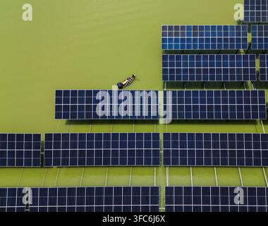 Vue aérienne du parc solaire de Sirajganj de 68 MW avec un petit bateau naviguant entre des panneaux solaires flottants à Sirajganj, division de Rajshahi, Bangladesh. Banque D'Images