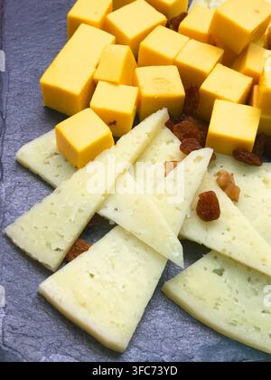 Fromages variés avec raisins secs sur une assiette en ardoise. Banque D'Images