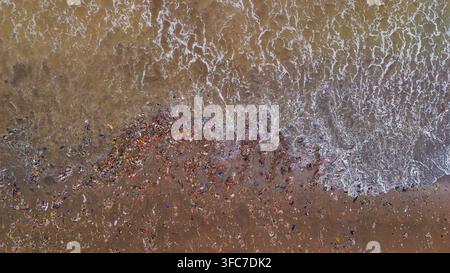 Vue aérienne des déchets plastiques et des débris déposés par les vagues de l'océan sur la plage de sable en Indonésie. Banque D'Images
