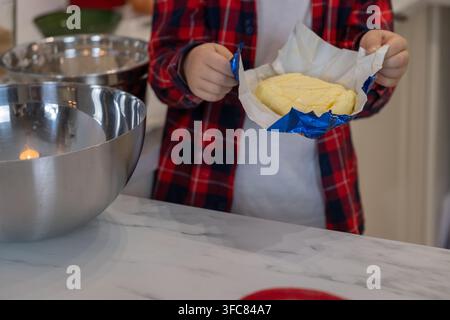 Enfant tenant du beurre en préparant la pâte à pain d'épices pour les biscuits de Noël Banque D'Images