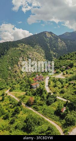 Vue aérienne verticale d'une église abandonnée et penchée dans le village de Ropoto, détruite par un glissement de terrain et entourée de pentes forestières montagneuses vertes, photo de stock verticale Banque D'Images