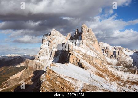 Sommets enneigés du Seceda illuminés par la lumière du soleil sous des nuages dramatiques dans les Dolomites. Paysage montagneux avec des formations calcaires abruptes et une chute de neige fraîche Banque D'Images