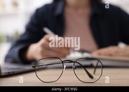 Mots-clés. Verres sur la table et femme écrivant dans un carnet, mise au point sélective Banque D'Images