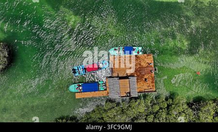 Vue aérienne d'un quai en bois entouré d'une eau verte claire avec plusieurs petits bateaux amarrés à proximité à Monte Cristi, province de Monte Cristi, République dominicaine Banque D'Images