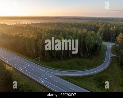 Vue aérienne de l'échangeur autoroutier A2 E77 près de Straujiupite, Lettonie, au lever du soleil avec forêt et brume matinale Banque D'Images