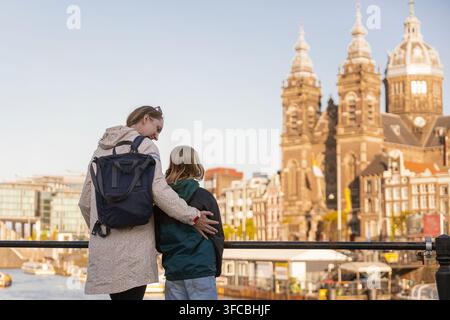 Une mère et sa fille se tiennent près d'un canal à Amsterdam, contemplant ensemble la ville lors de leur voyage familial aux Pays-Bas. Banque D'Images