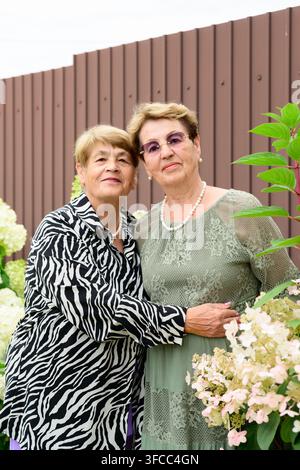 Portrait authentique de deux sœurs russes souriantes de 80 et 75 ans regardant l'appareil photo près d'hortensias en fleurs dans un jardin d'été à Ru Banque D'Images