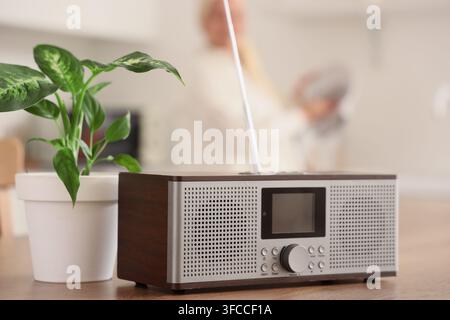 Récepteur radio avec une plante sur la table devant une femme âgée faisant la vaisselle dans la cuisine, gros plan Banque D'Images