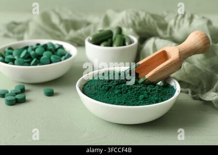 Bol de poudre de spiruline avec capsules et comprimés sur fond vert Banque D'Images