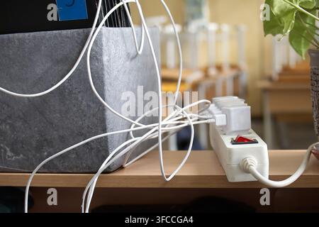 Cordon d'alimentation multiprise avec câbles et chargeurs emmêlés sur un bureau, capturant une esthétique d'espace de travail désordonné avec une lumière ambiante douce, ide Banque D'Images