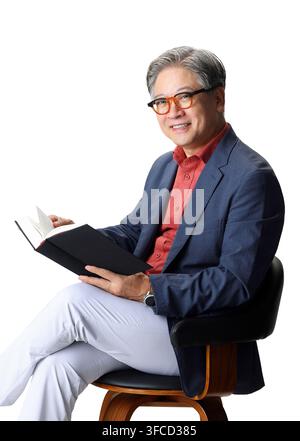 Professionnel senior coréen expérimenté lisant un livre dans un portrait de studio Banque D'Images