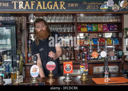 Le propriétaire Oli Carter-Esdale se tient derrière le comptoir du bar au Trafalgar Freehouse à South Wimbledon, Londres, servant une bière de fût indépendante authentique. Banque D'Images