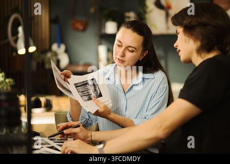 Couple jeune multiethnique examinant des photographies imprimées au bureau, collaborant sur un projet créatif. Image adaptée à l'enseignement des arts ou au marketing d'agences de design Banque D'Images