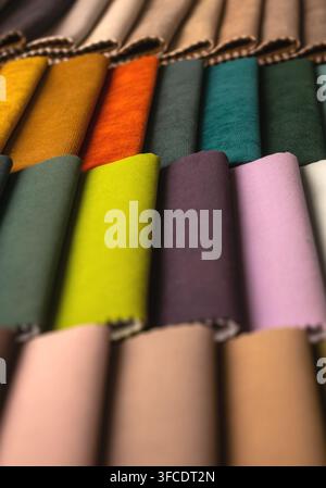 Échantillons de tissu roulés dans des couleurs vives en gros plan. Empilement vertical de motifs textiles pour tapisseries et rideaux. Rouleaux de matériaux colorés exposés Banque D'Images