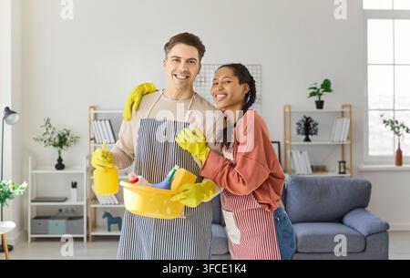 Couple heureux faisant le ménage à la maison, portrait avec gants et fournitures Banque D'Images